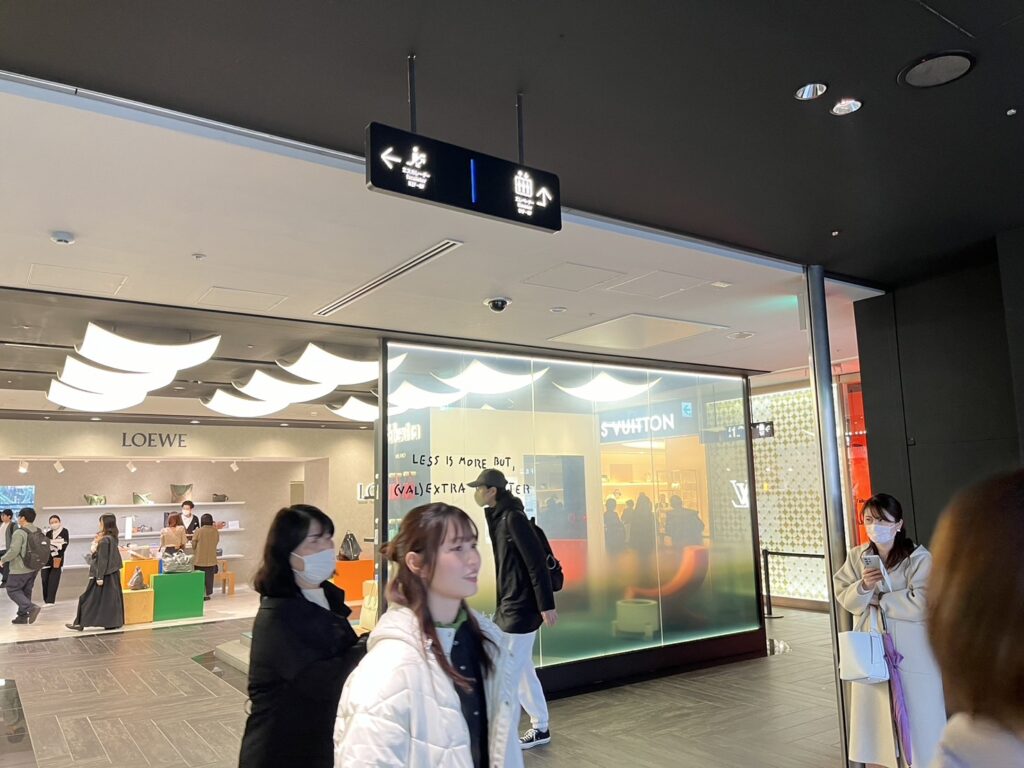 西武池袋本店の館内で、エレベーター方向を示す案内板と周辺店舗の様子を写した写真