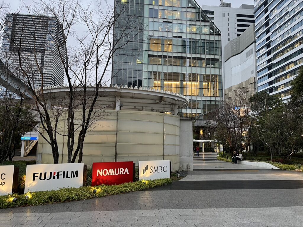 豊洲駅6b番出口付近、FUJIFILM・NOMURA・SMBCなどの看板が並ぶ広場の様子を写した写真