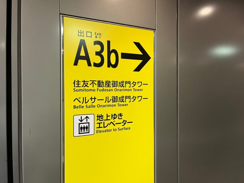 御成門駅A3b出口方面を示す地下通路の案内サイン。住友不動産御成門タワーとエレベーター方向が示された黄色い標識。