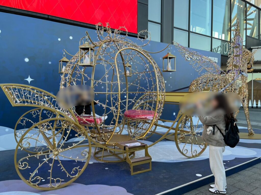 ゴールドの馬車型フォトスポット。数組の来場者が撮影待ちしている様子。